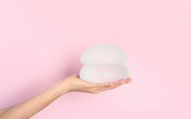 Hand, die Brustimplantate hält, symbolisiert Grösse und Form von Brustimplantaten